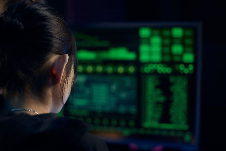 An analyst studies live data on a screen in a darkened monitoring room.