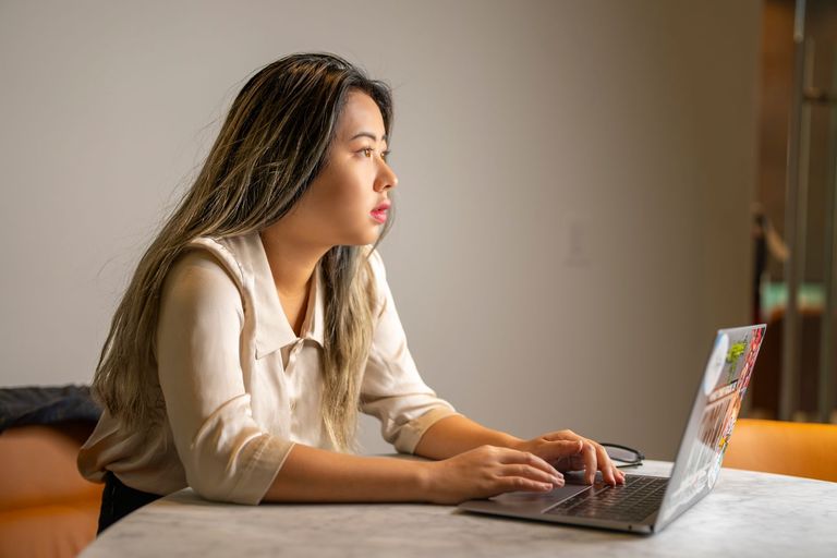 A young woman concentrates on her work at a laptop.