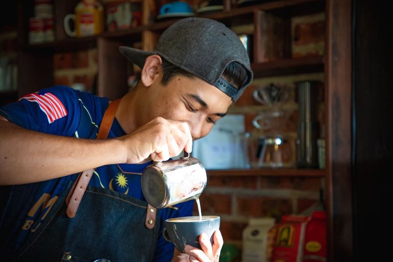 A barista pours latte art into a cup.
